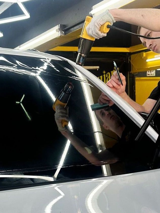 A man is installing a window tint on a car.