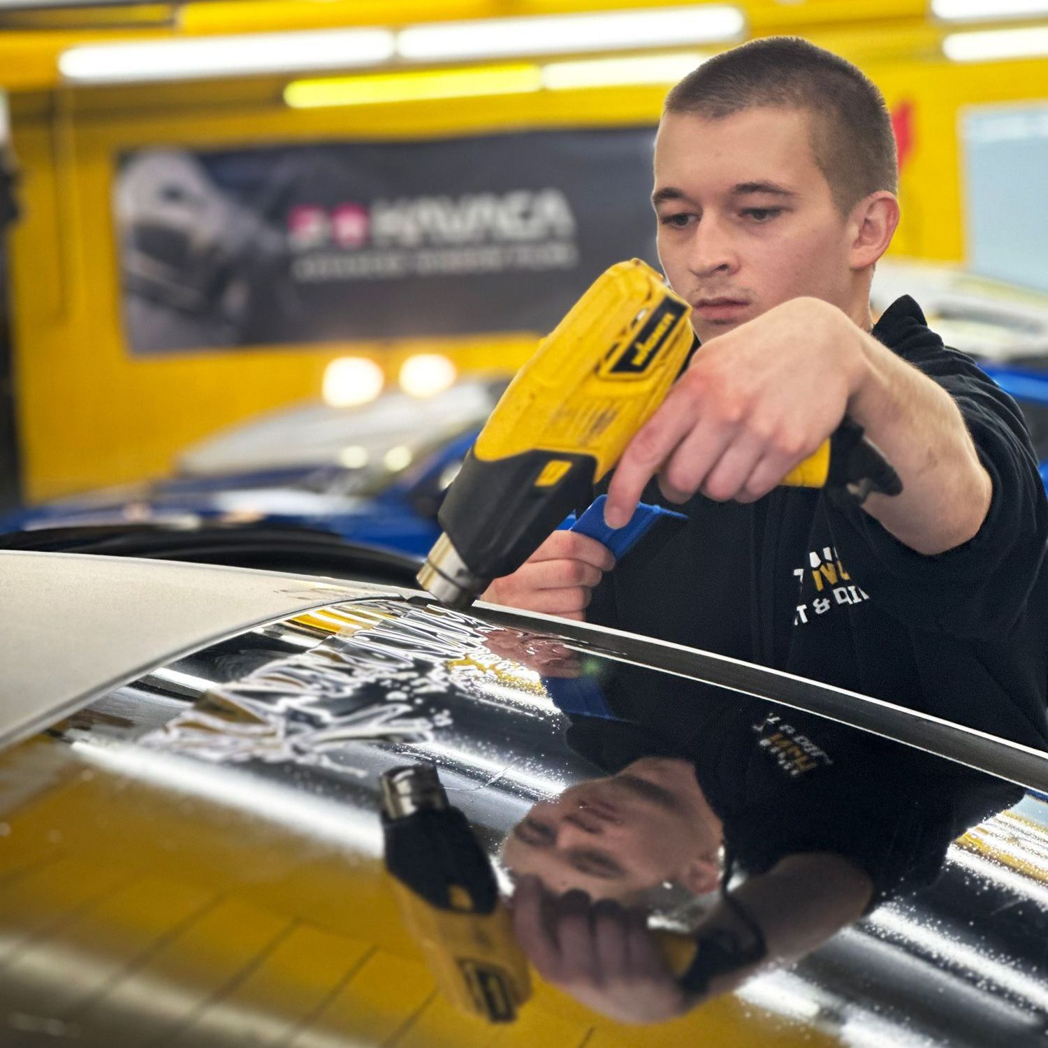 A man is working on a car in front of a sign that says hyundai