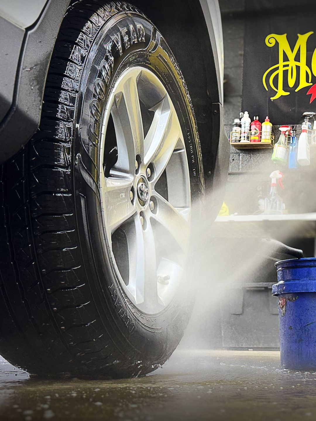 A close up of a car wheel being sprayed with water