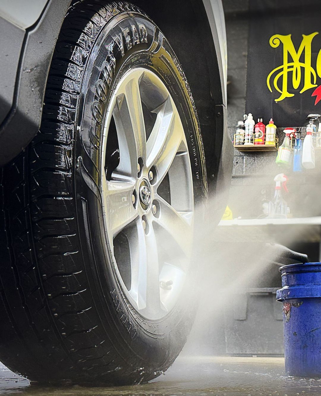 A car is being washed in front of a sign that says meguiar 's