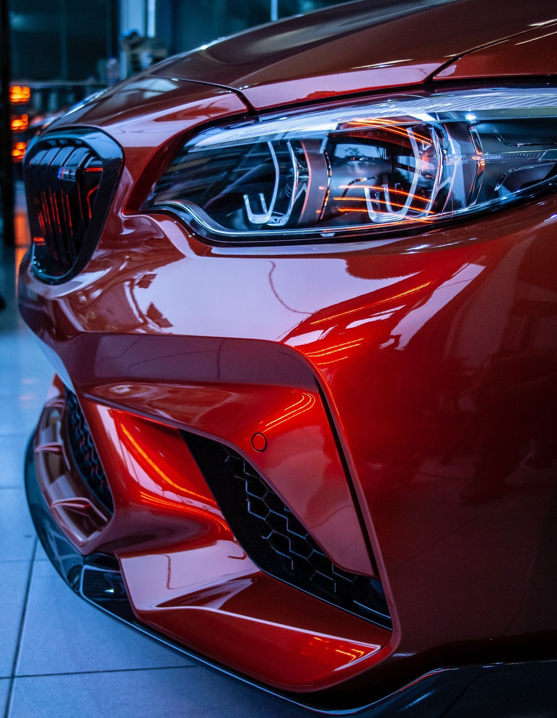 A close up of the front of a red bmw m2.