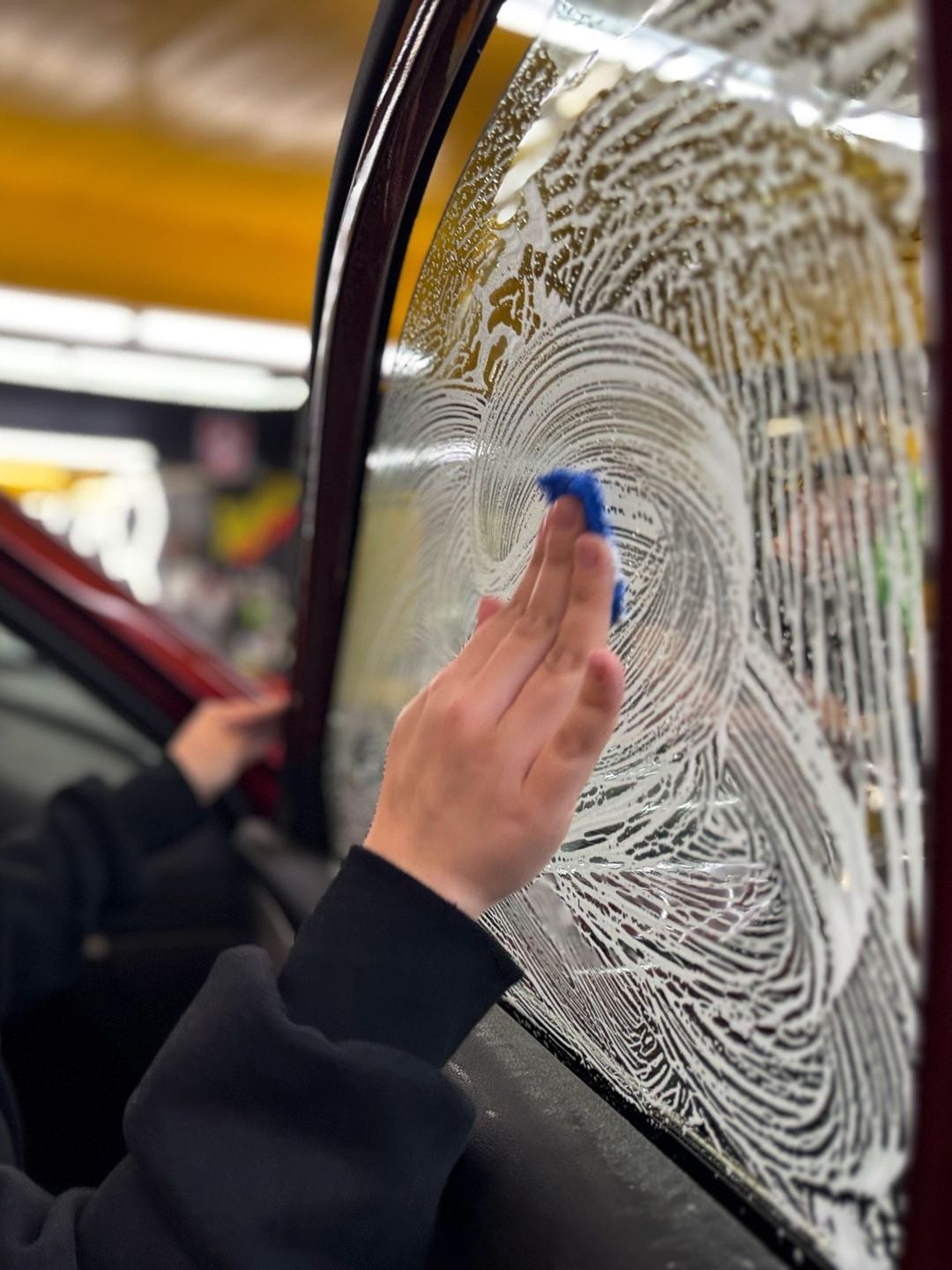 A person is cleaning a car window with a sponge.