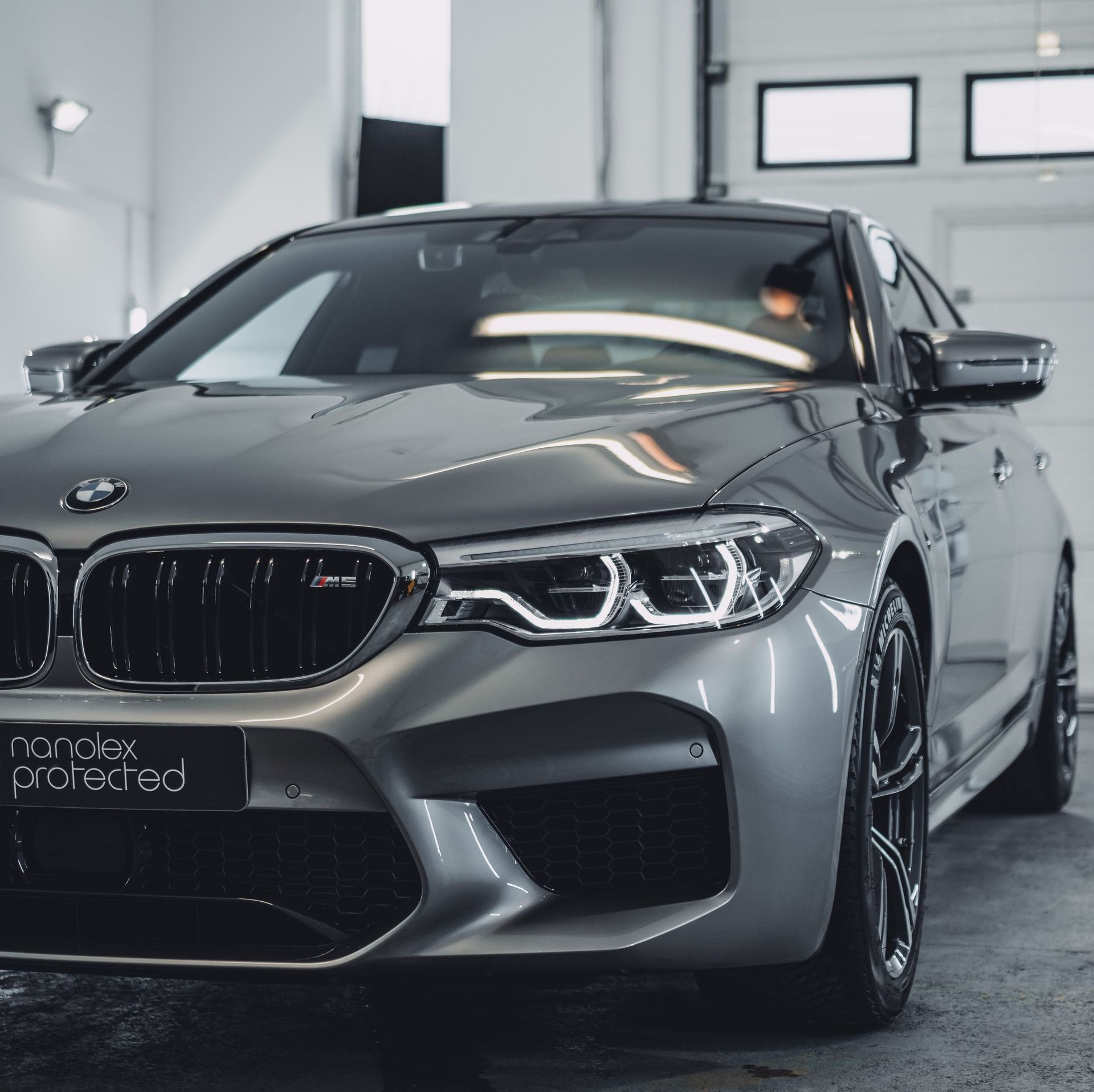 A bmw is parked in a garage with a sign that says ronex protected