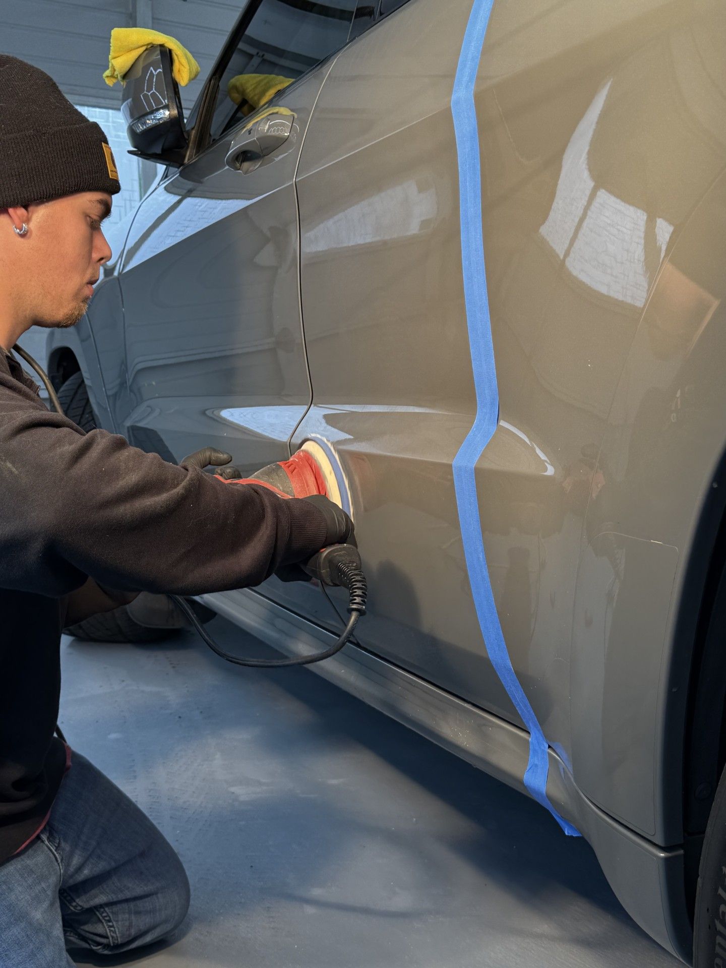 A person wearing black gloves is polishing a car with a machine