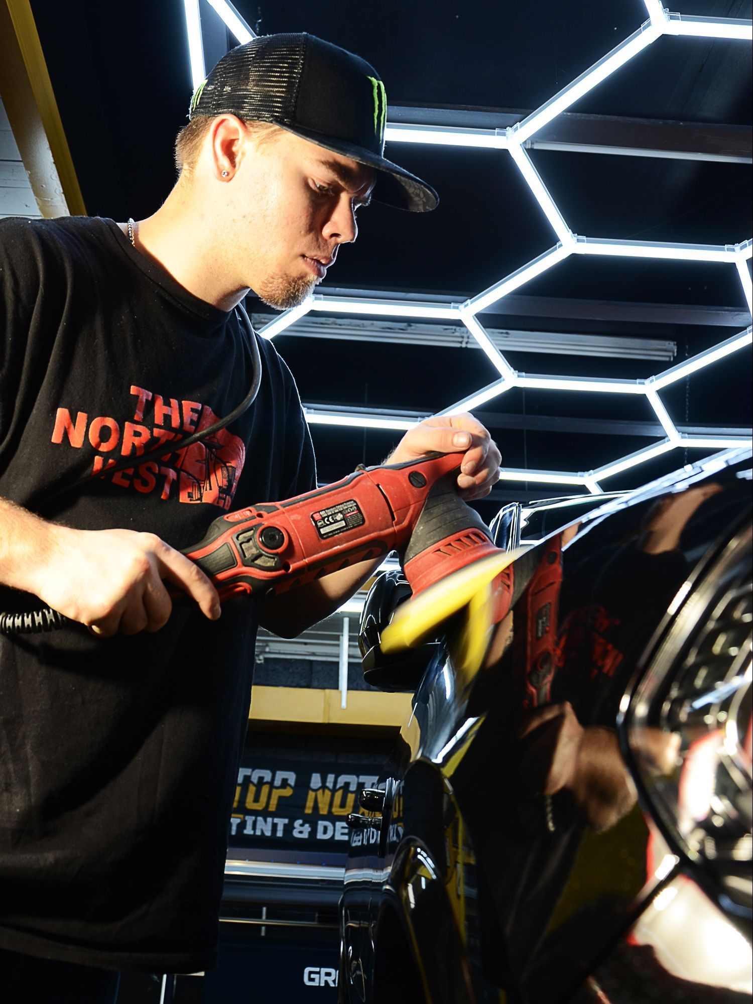 A man is polishing a car with a machine.