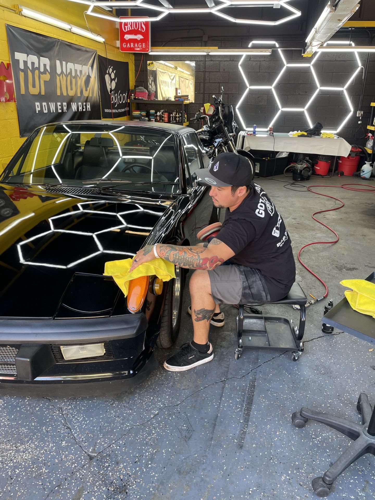 A man is wiping a car with a towel in a garage during paint correction.