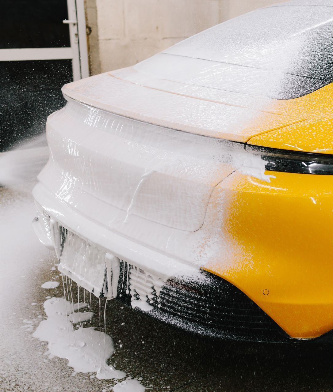 A woman is cleaning the windshield of a car in a car wash.