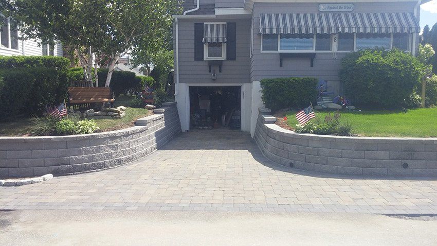 A driveway leading to a house with a garage and a brick wall.