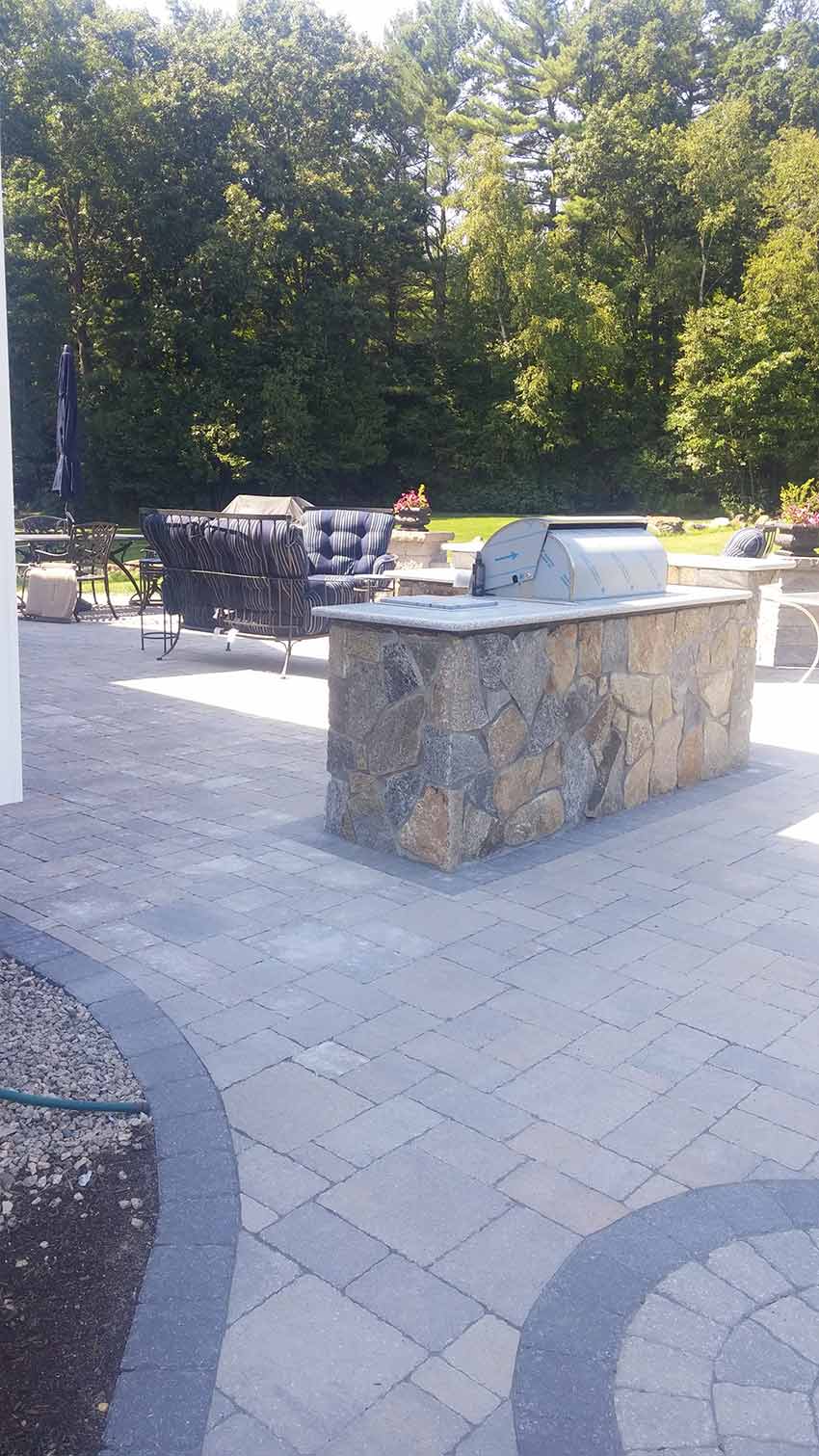 A patio with a stone counter top and a grill.