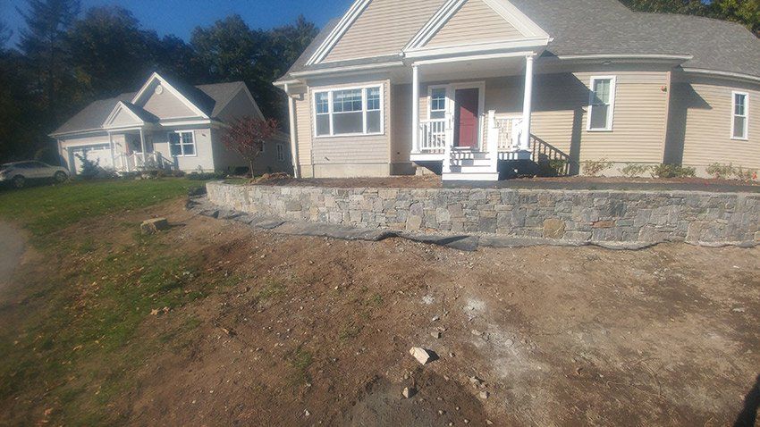 A house with a stone wall in front of it.