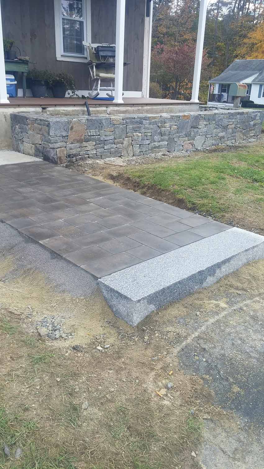 A stone walkway is being built in front of a house.