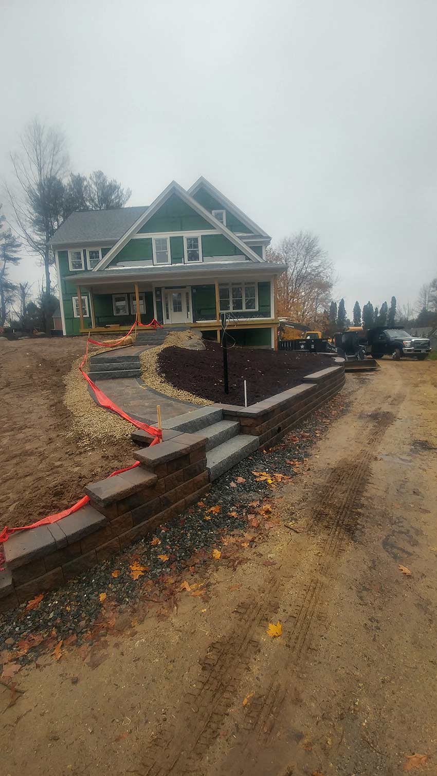 A large green house is being built next to a dirt road.