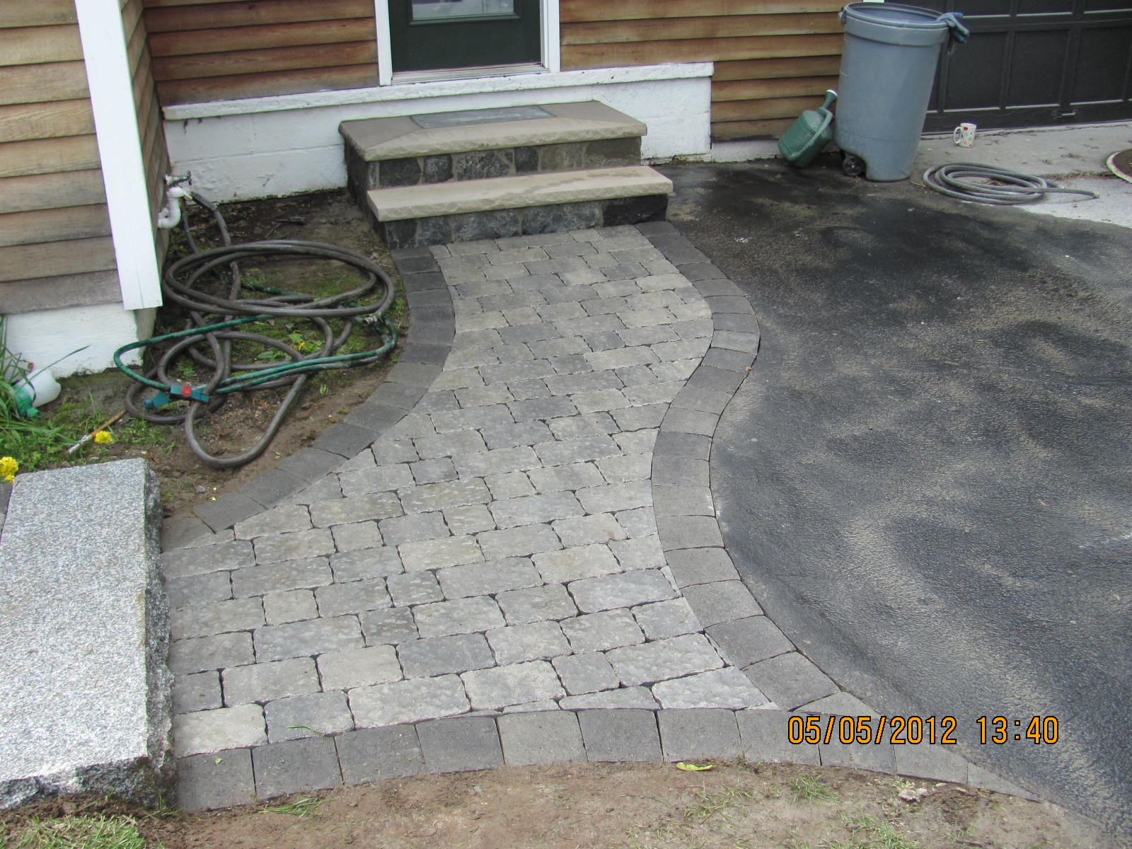 A walkway with steps and a hose in front of a house