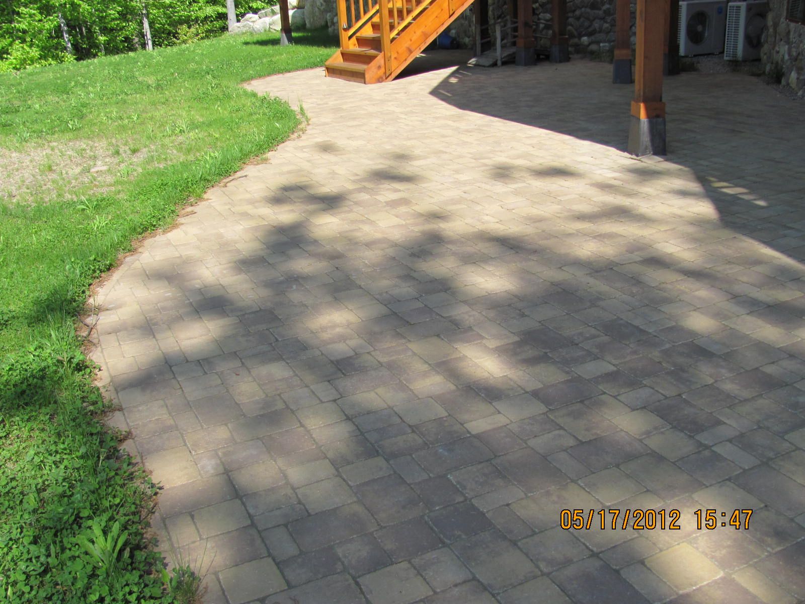 A brick walkway with a wooden staircase in the background