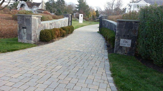 A brick walkway leading to a house in a residential area.