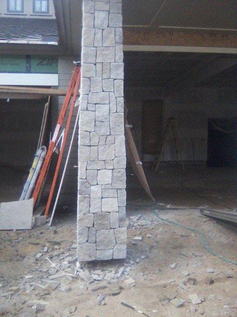 A large stone column is in the middle of a garage under construction