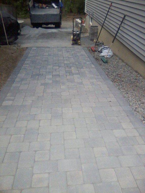 A truck is parked in a driveway next to a brick walkway.