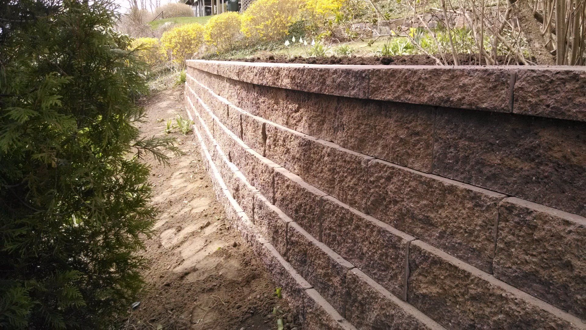 A brick wall is sitting on top of a dirt hill.