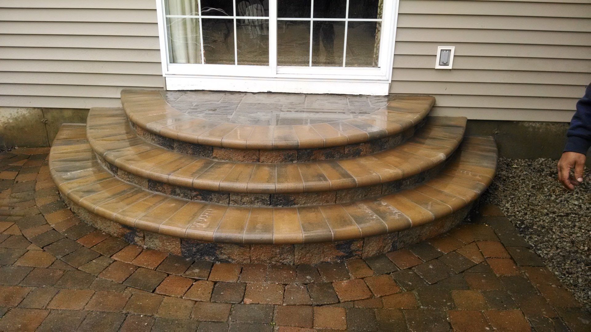 A man is standing next to a set of brick steps leading to a door.