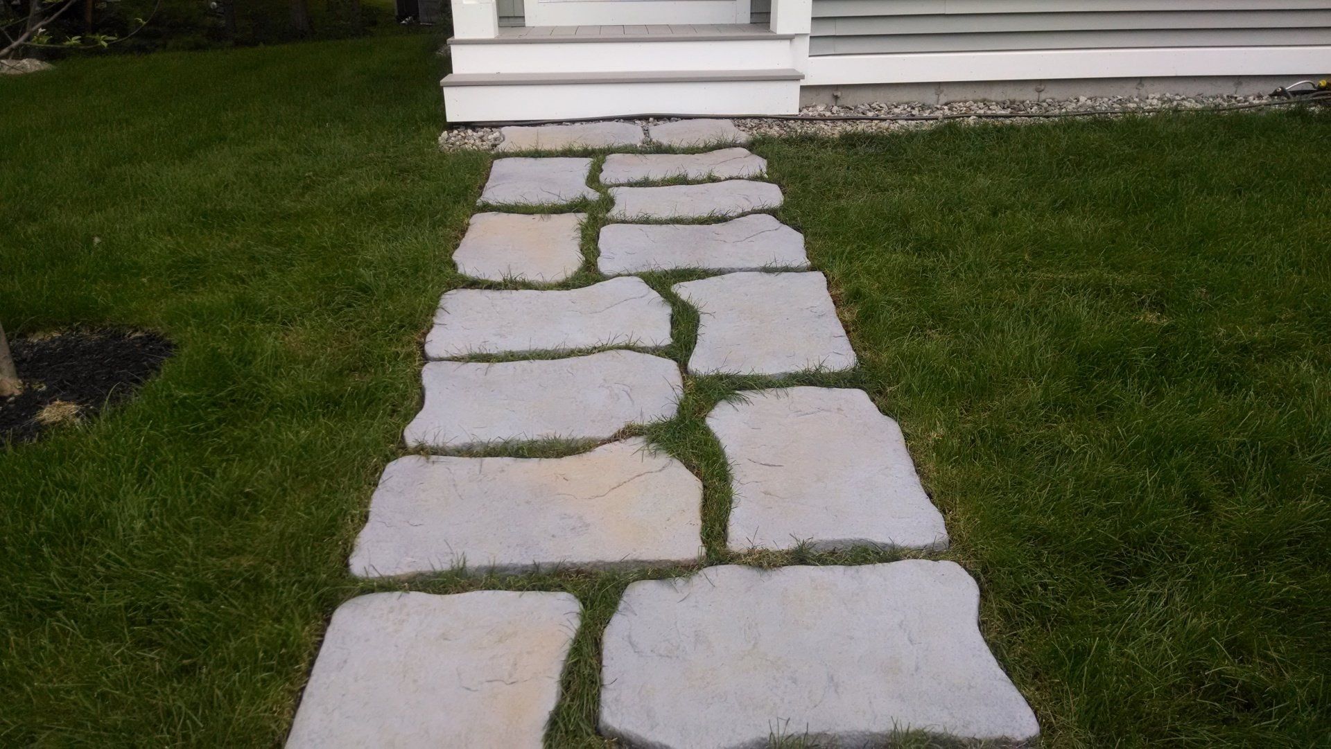 A stone walkway leading to a white house.