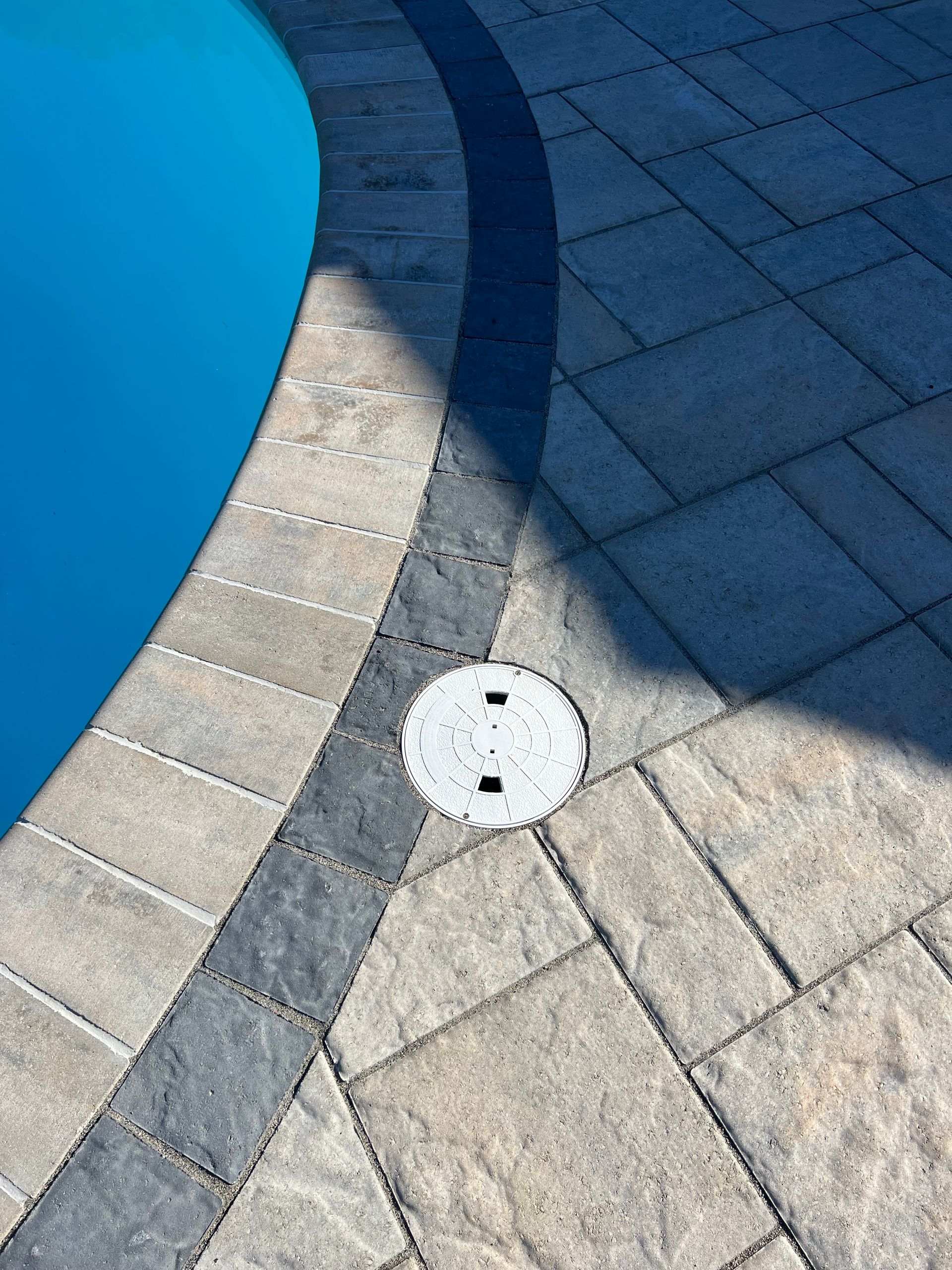 A white drain cover is on the side of a pool.