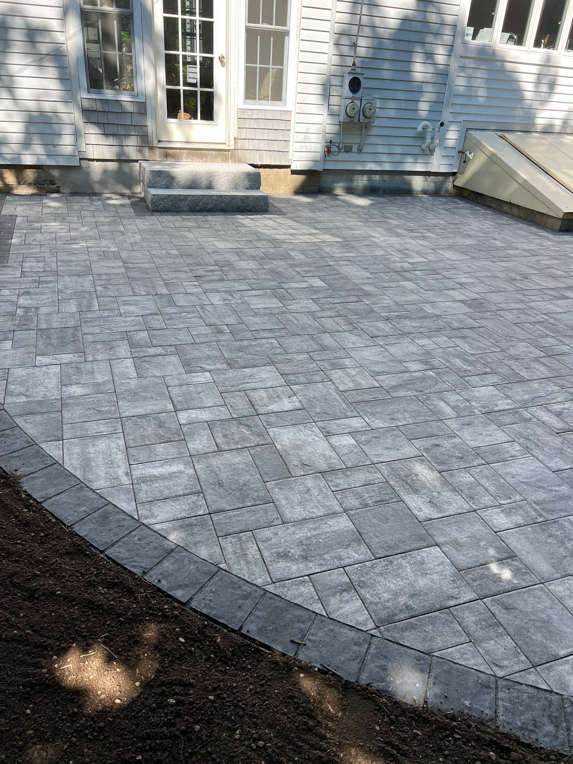 A brick patio is being built in front of a house.