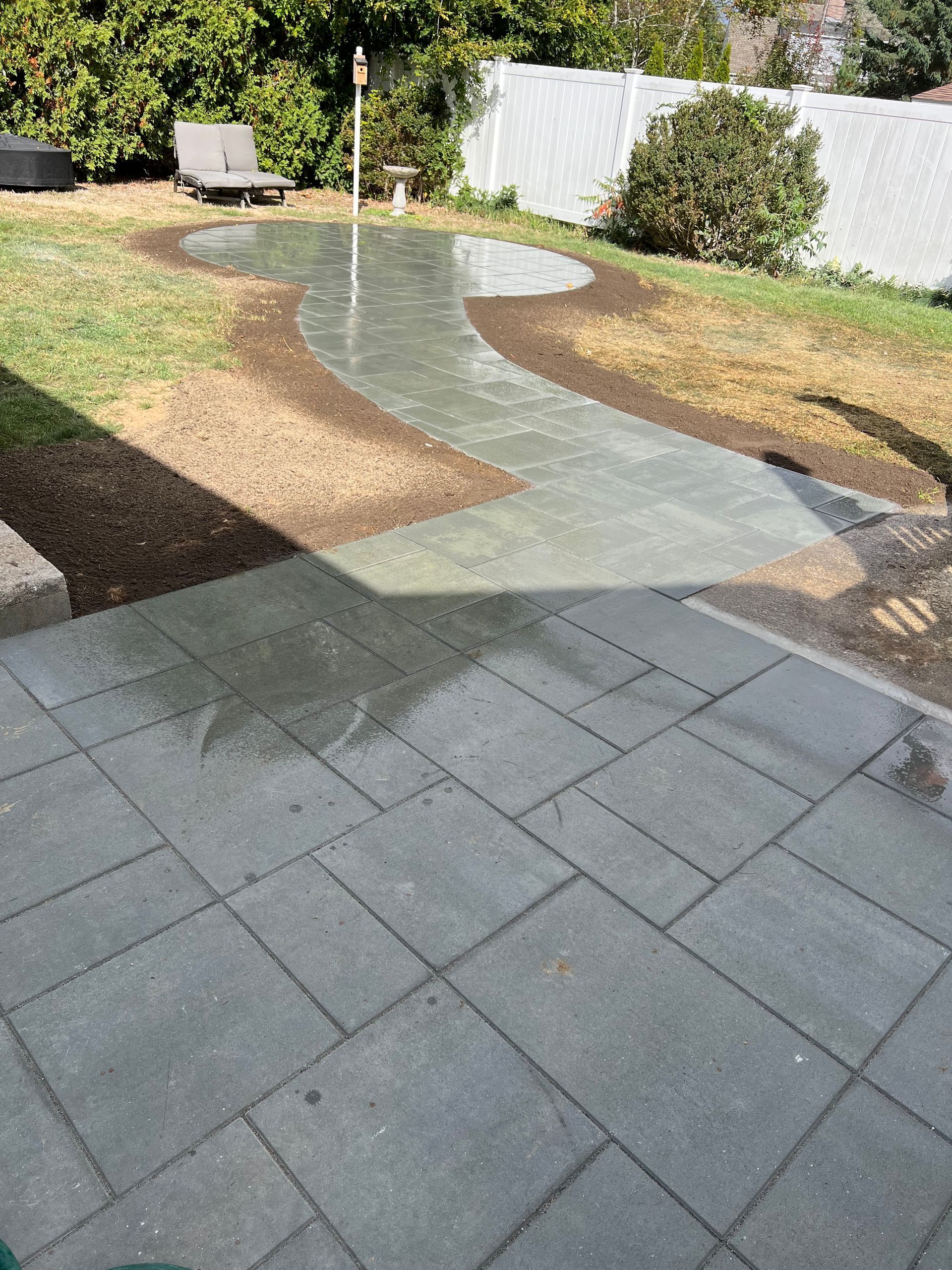 A patio in a backyard with a fence in the background.