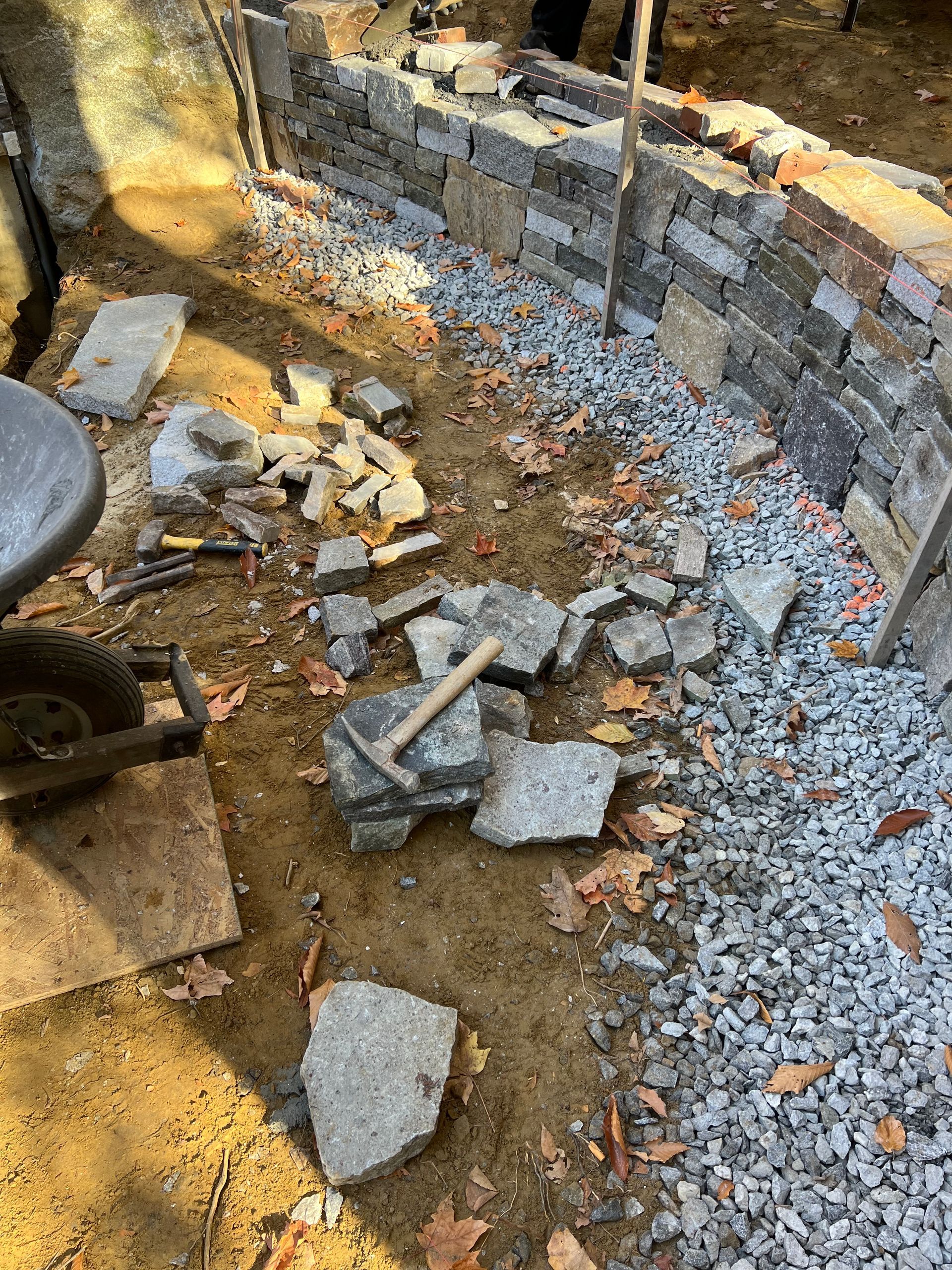 A wheelbarrow is sitting on the ground next to a pile of rocks and gravel.
