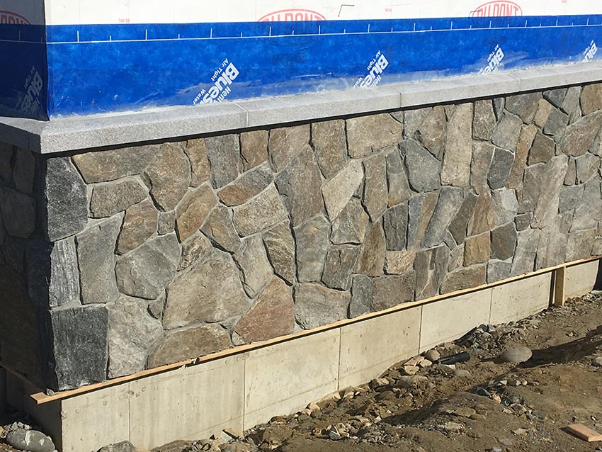 A stone wall is being built on the side of a building.