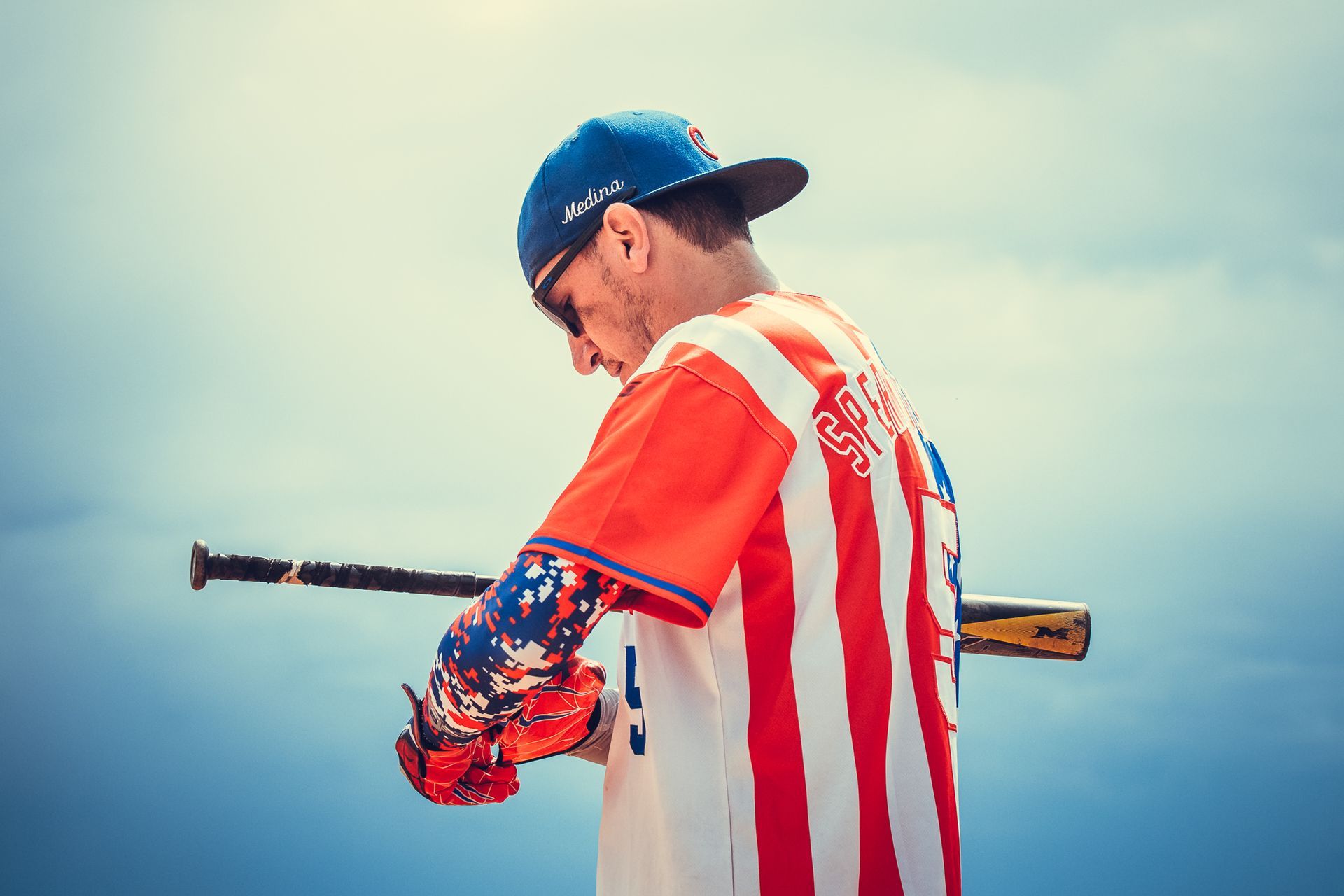 Male softball player adjusts his batting gloves before his at-bat.