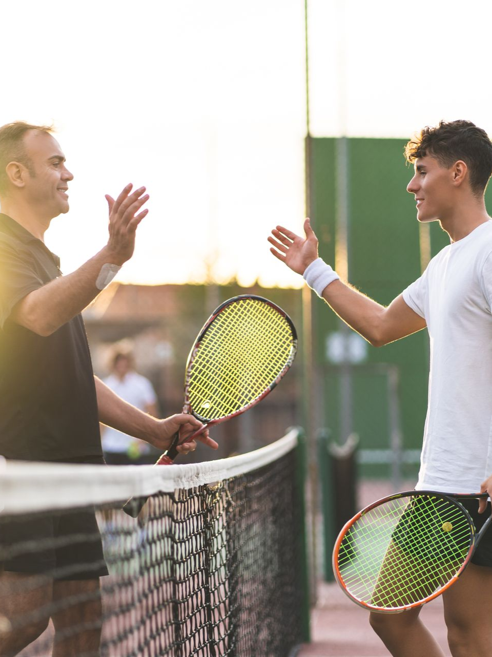 Two men high five each other after a tennis match.