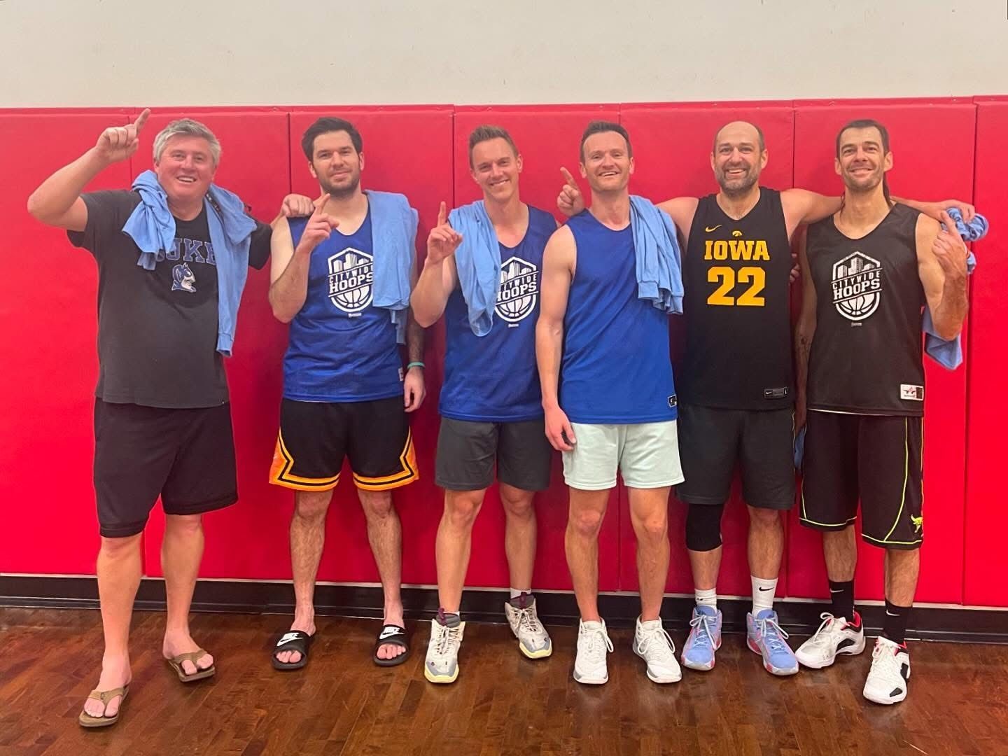 Male basketball players celebrate their championship with new t-shirts.