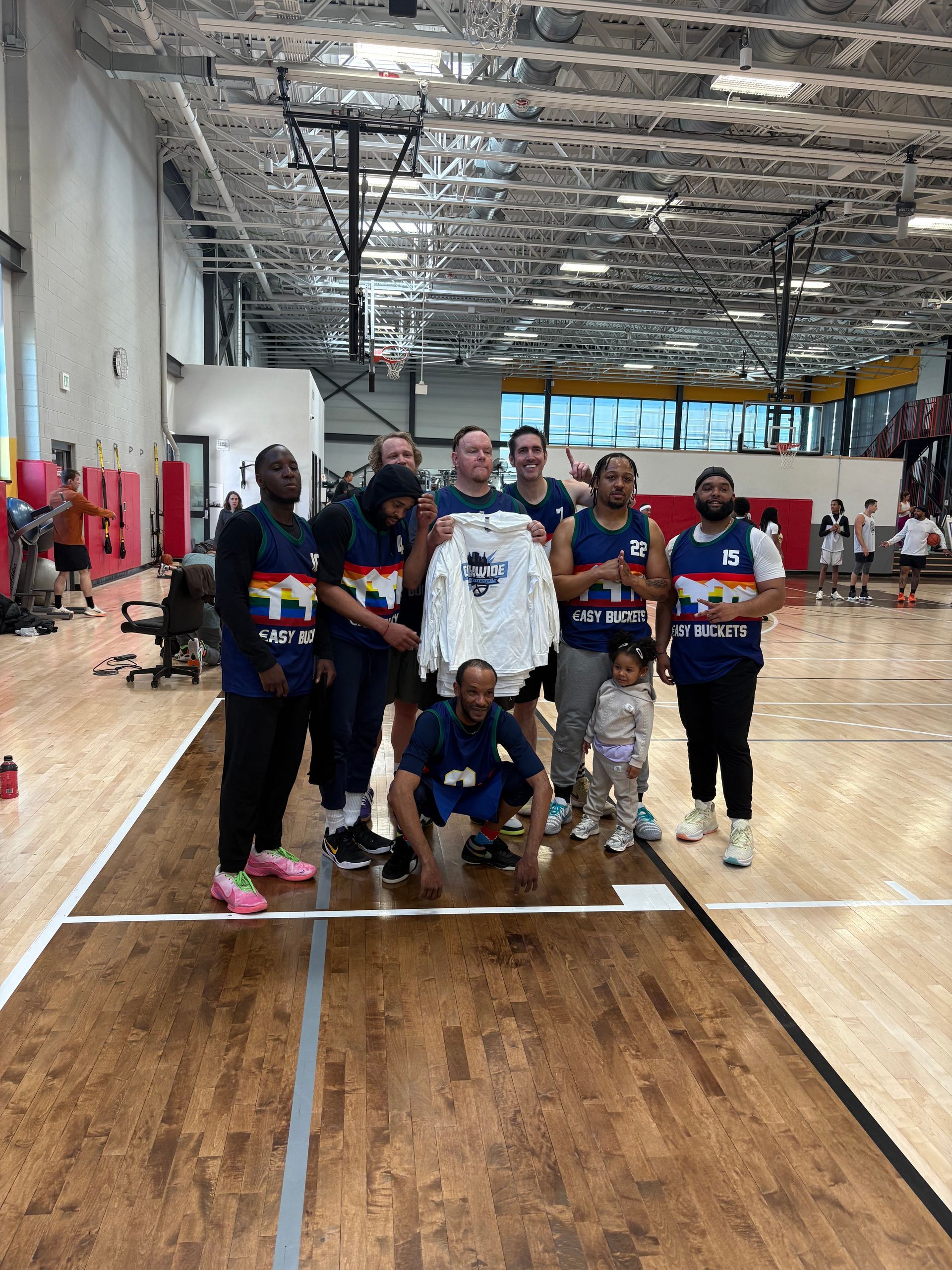 Male basketball players celebrate their championship with new t-shirts.