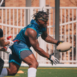 Male flag football player running with the ball during a game.