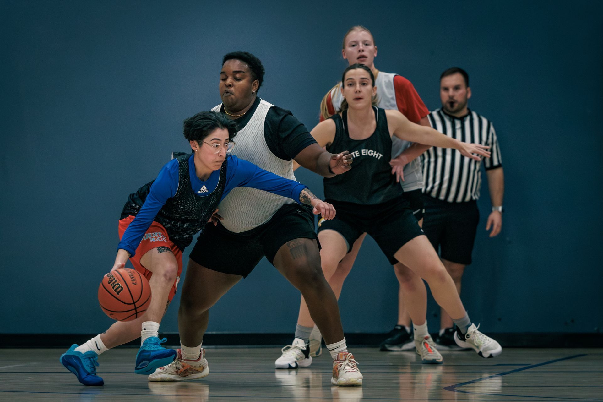 Female basketball players against a blue wall background.