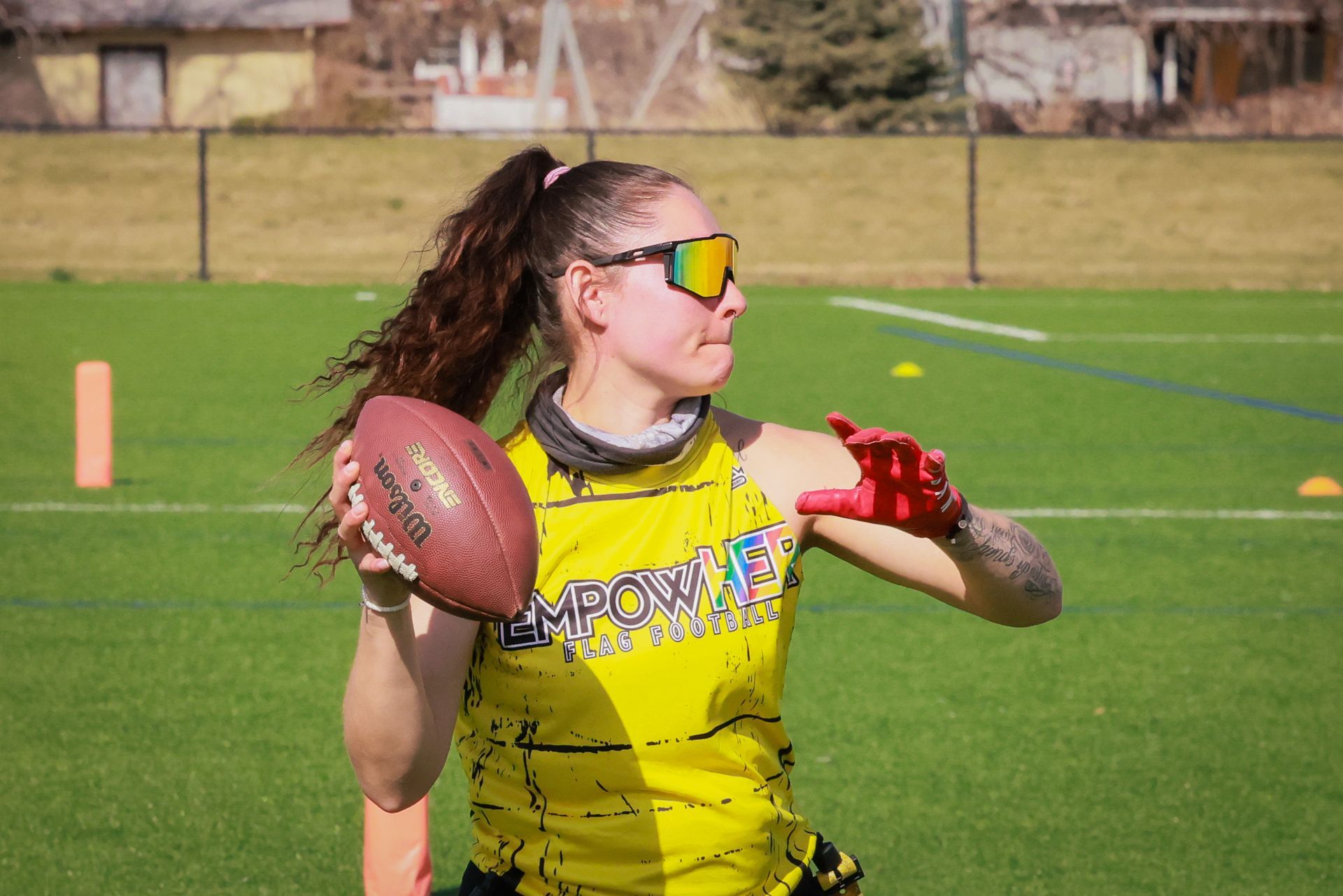 Female flag football quarterback winding up to throw the football.