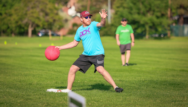 Adult kickball player throwing the ball to force an out.