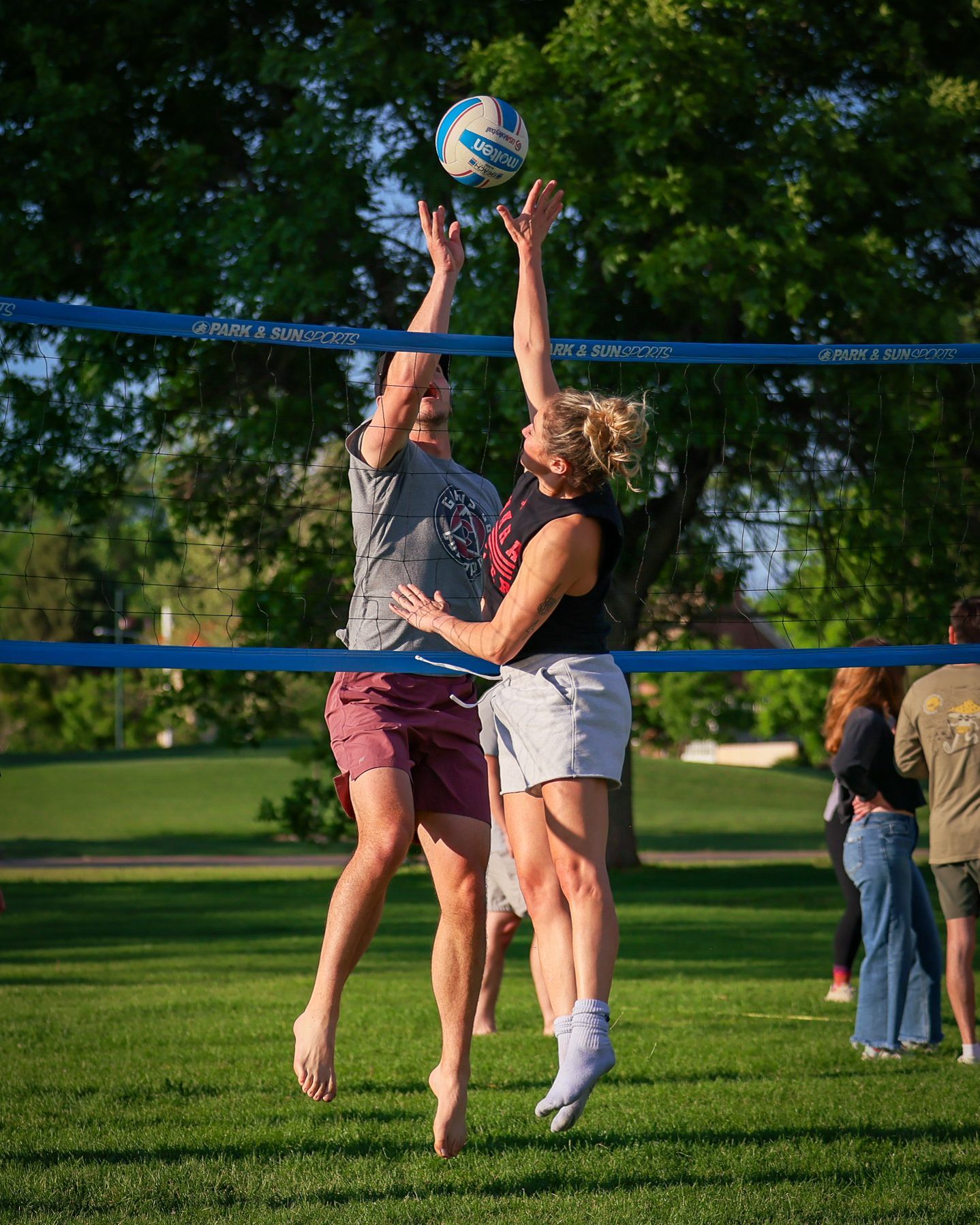 A male and a female volleyball players jump to tip the ball.