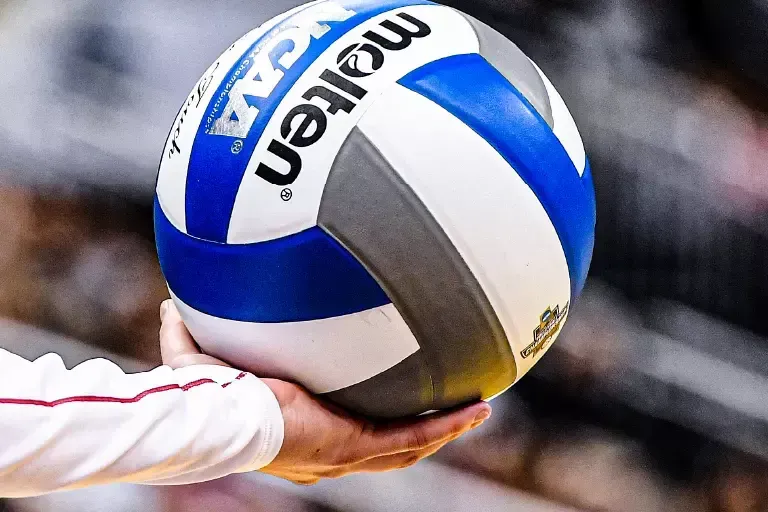 Indoor volleyball player prepares to serve the ball.