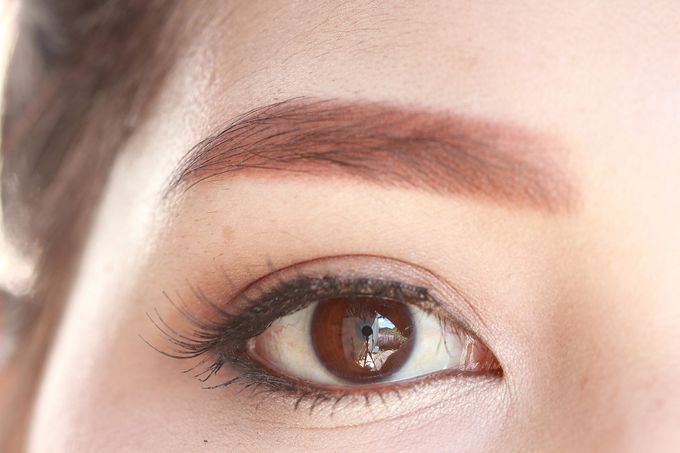 Primo piano di un occhio marrone con sopracciglio, eyeliner e trucco leggero.