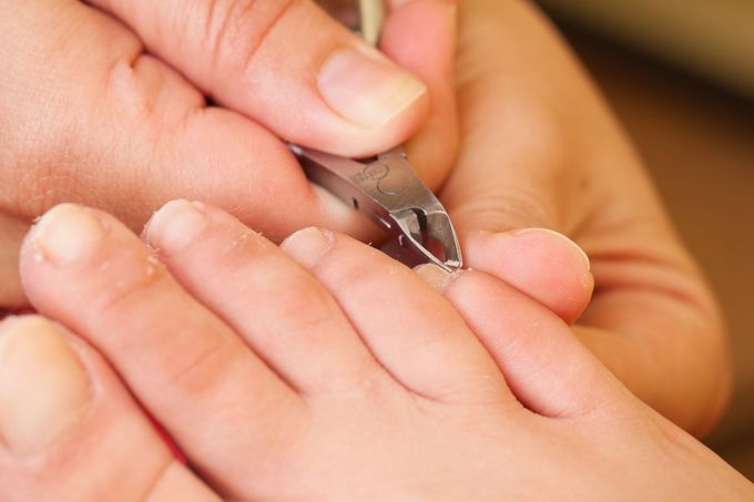 Mani che tagliano le unghie dei piedi con un tagliaunghie (primo piano)