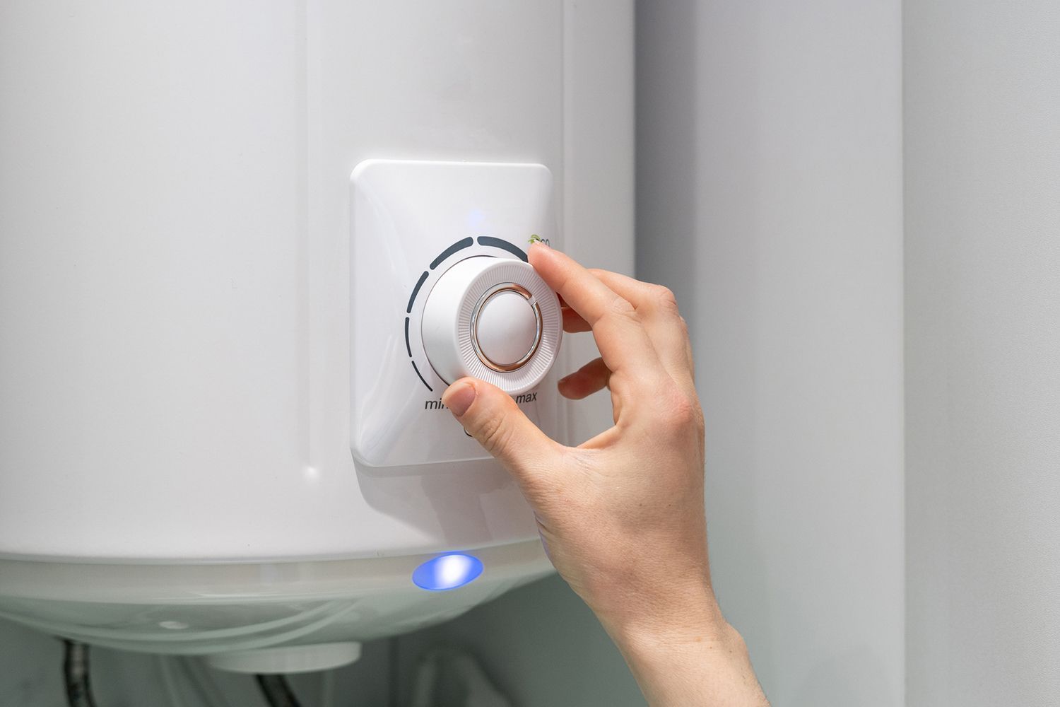 A person is adjusting the temperature of a water heater.