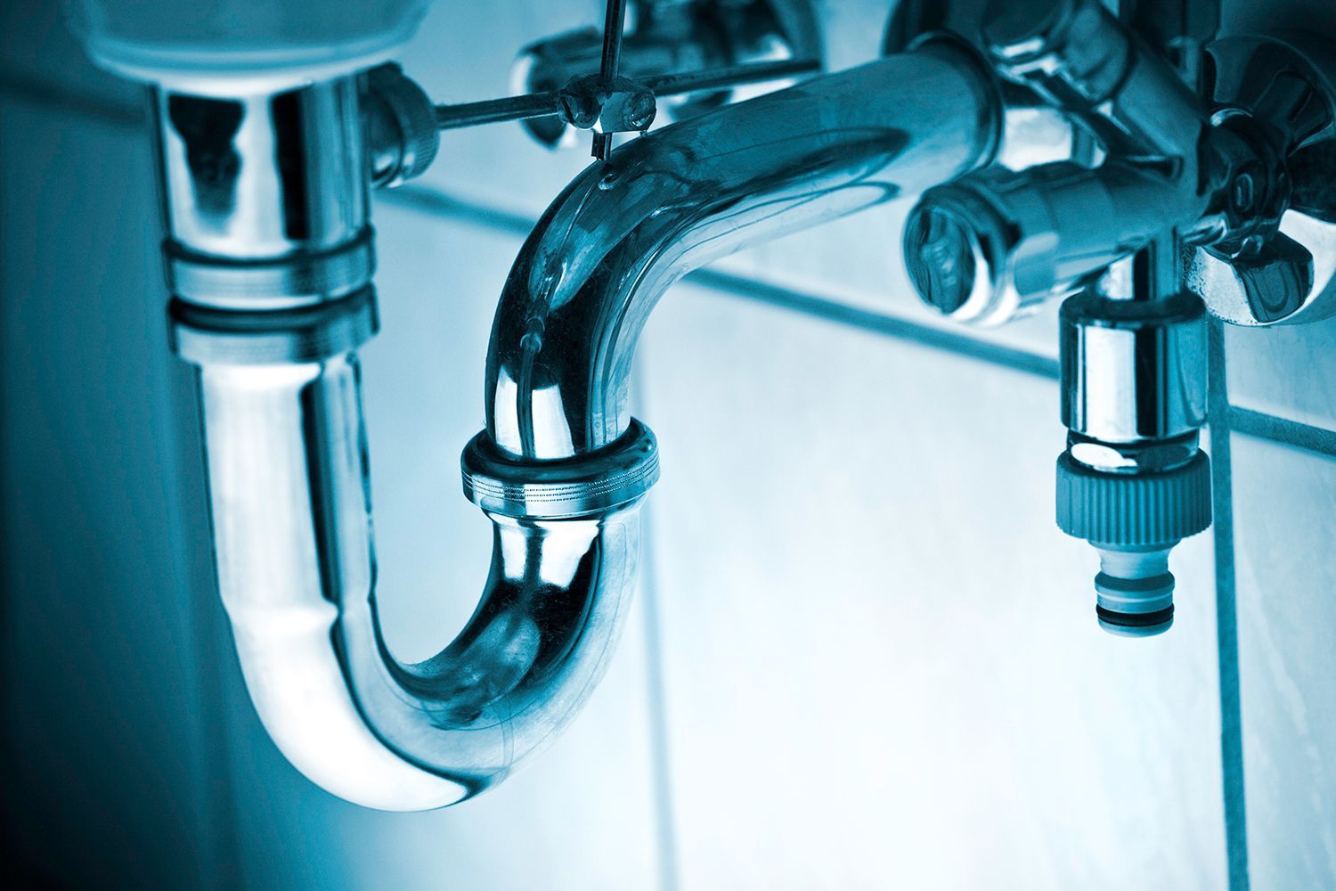 A plumber is fixing a sink in a kitchen.