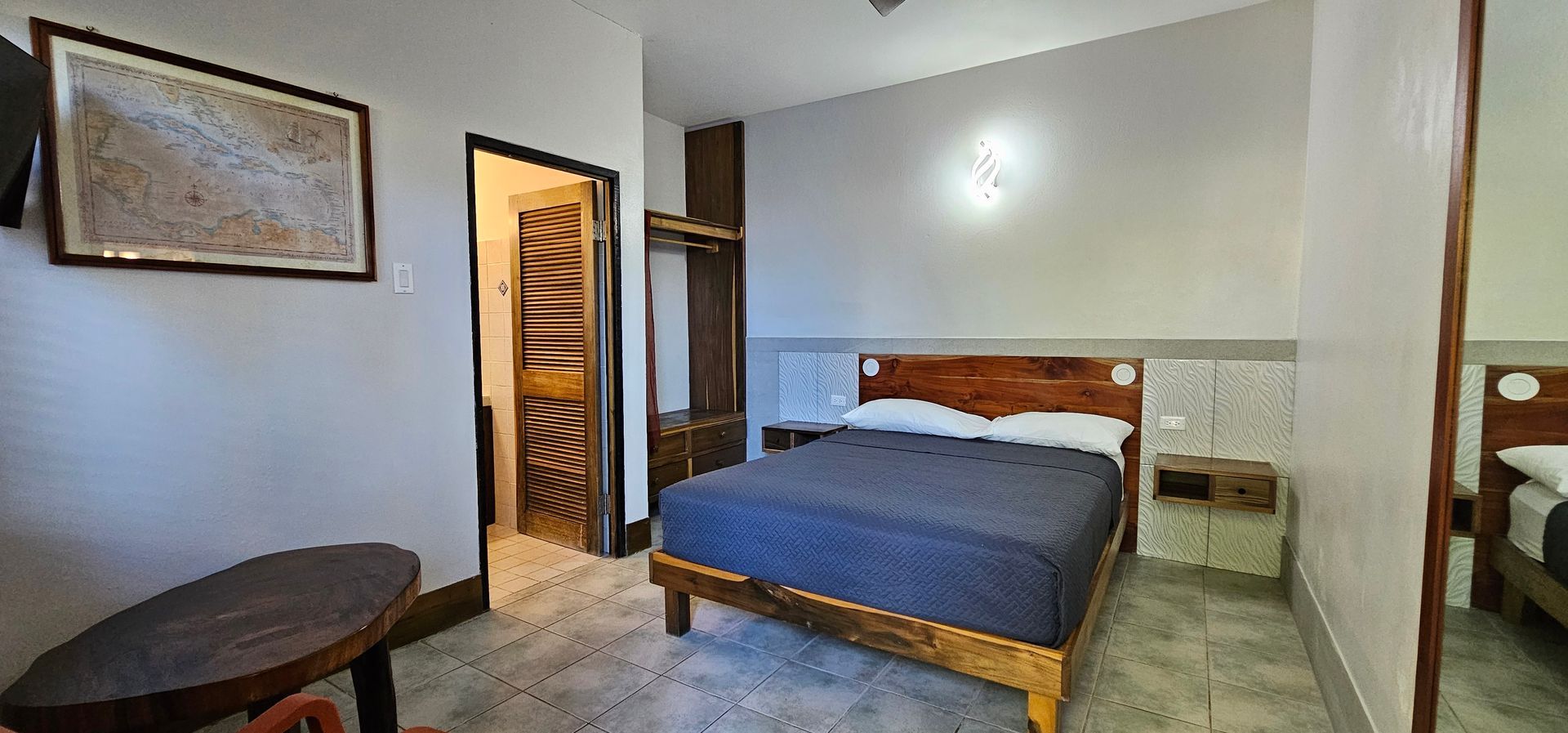 Bedroom interior with a bed, table, closet, and a doorway leading to a bathroom.