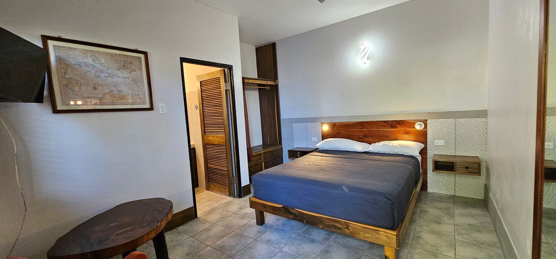 Bedroom with a wooden bed frame, a round table, and a framed picture on the wall.