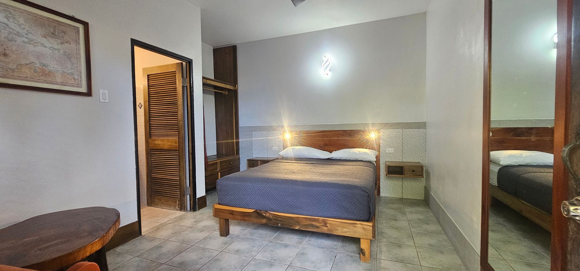 Bedroom with a bed, nightstand, closet, and open doors. The walls are light-colored.