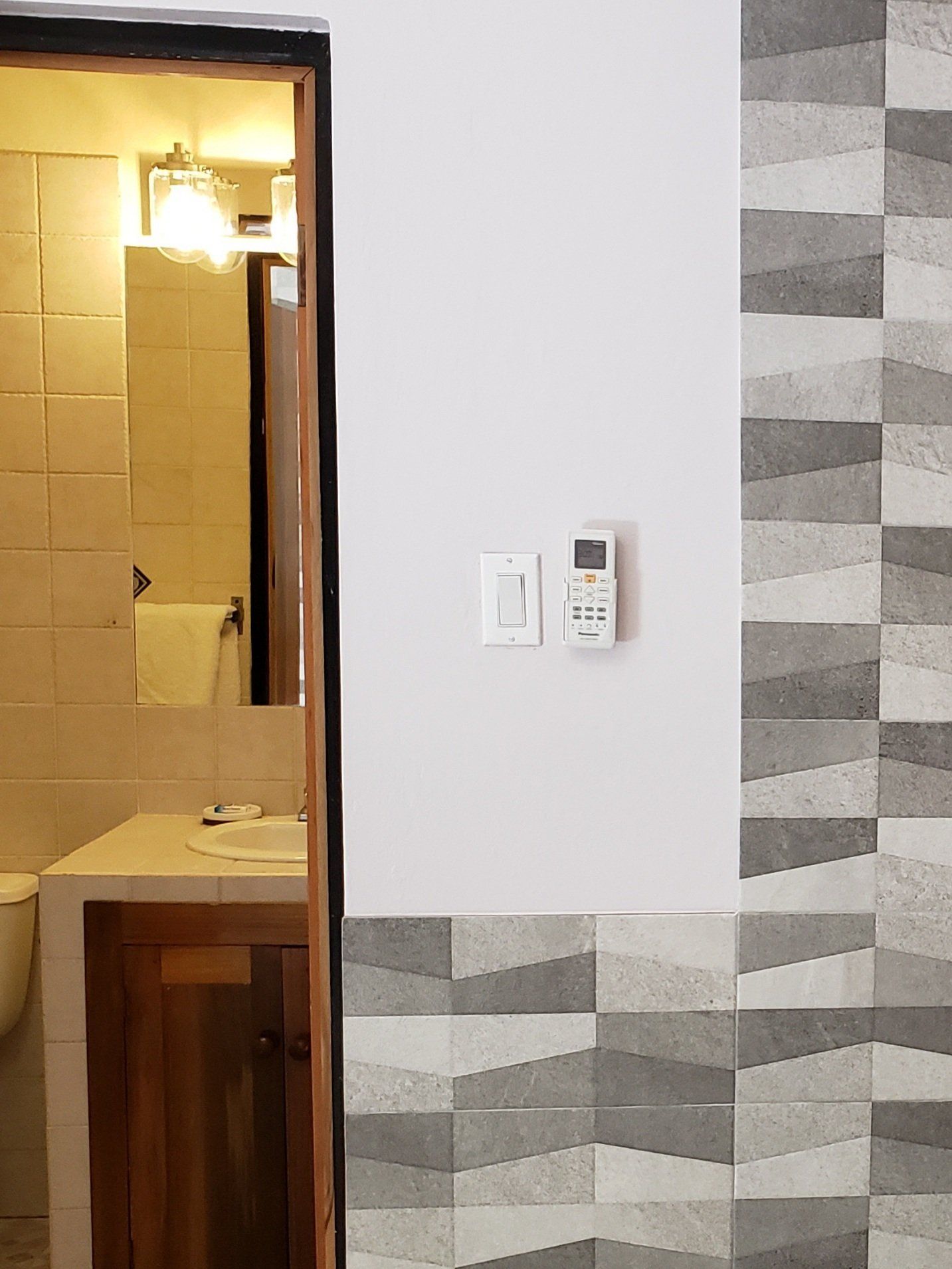 A bathroom with a sink and a remote control on the wall