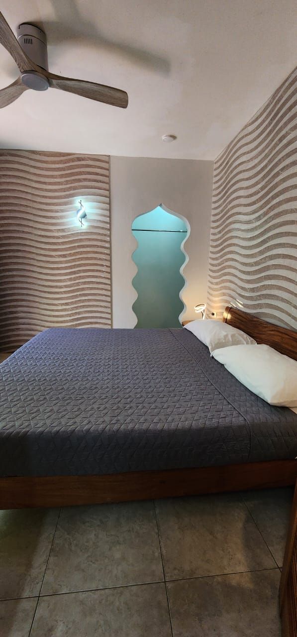 A bedroom with a large bed and a ceiling fan.