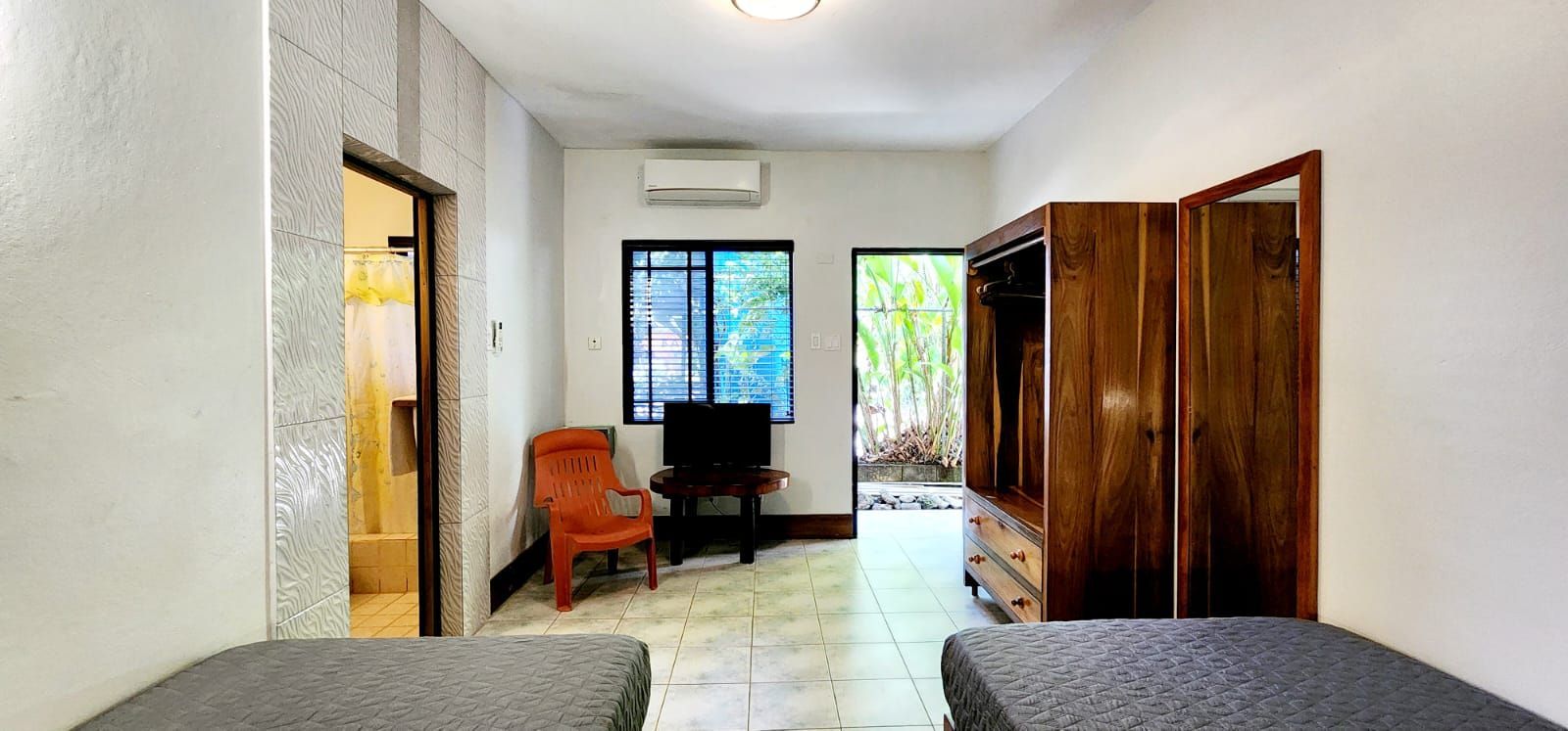 A bedroom with two beds , a chair , a television and a wardrobe.