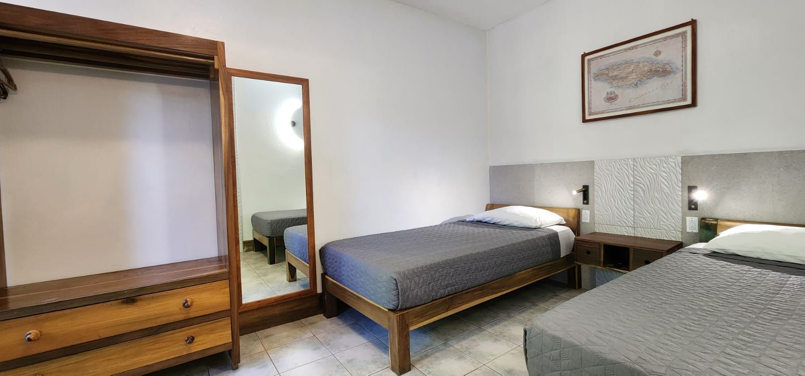 A bedroom with two beds , a dresser and a mirror.